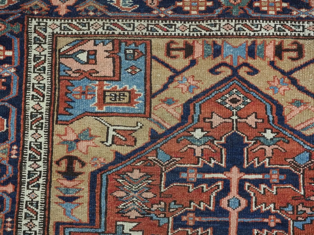An antique hand-knotted Persian Heriz rug featuring a central starburst medallion in teal, terracotta, and cream on a patterned ground with a multi-band geometric border. View VIII