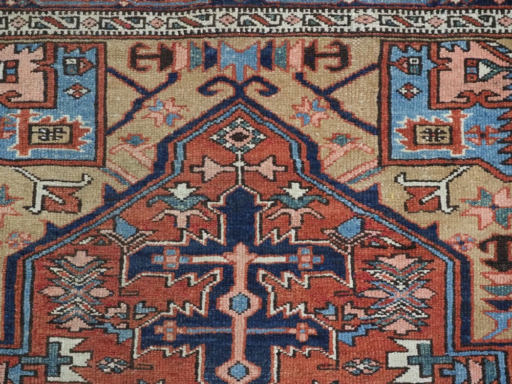 An antique hand-knotted Persian Heriz rug featuring a central starburst medallion in teal, terracotta, and cream on a patterned ground with a multi-band geometric border. View IX
