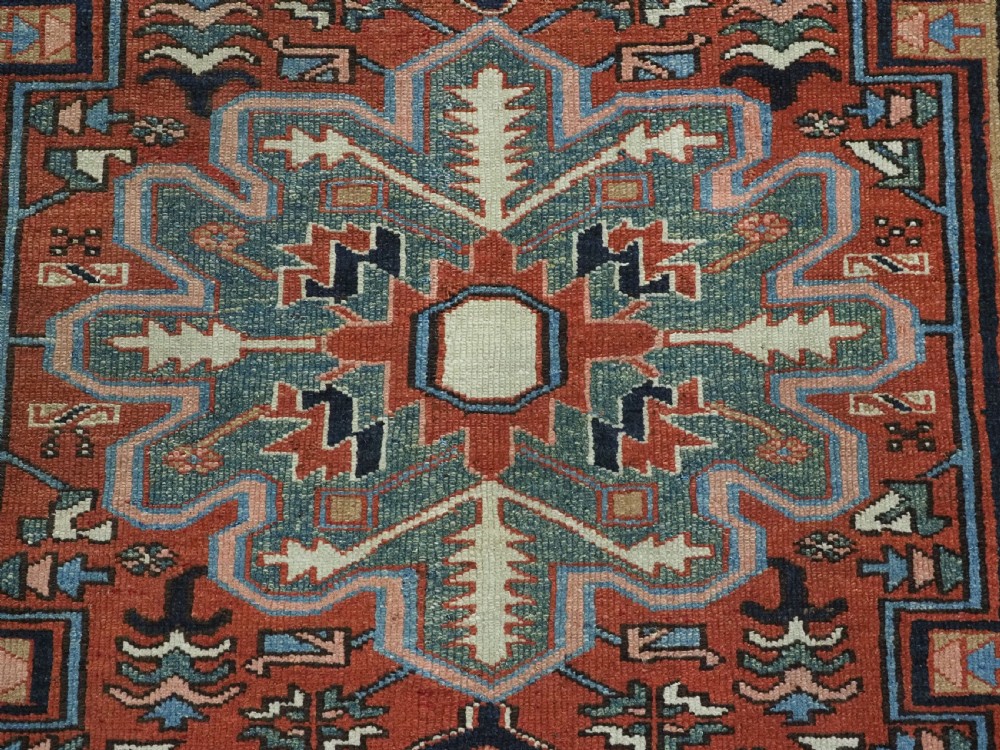 An antique hand-knotted Persian Heriz rug featuring a central starburst medallion in teal, terracotta, and cream on a patterned ground with a multi-band geometric border. View XI