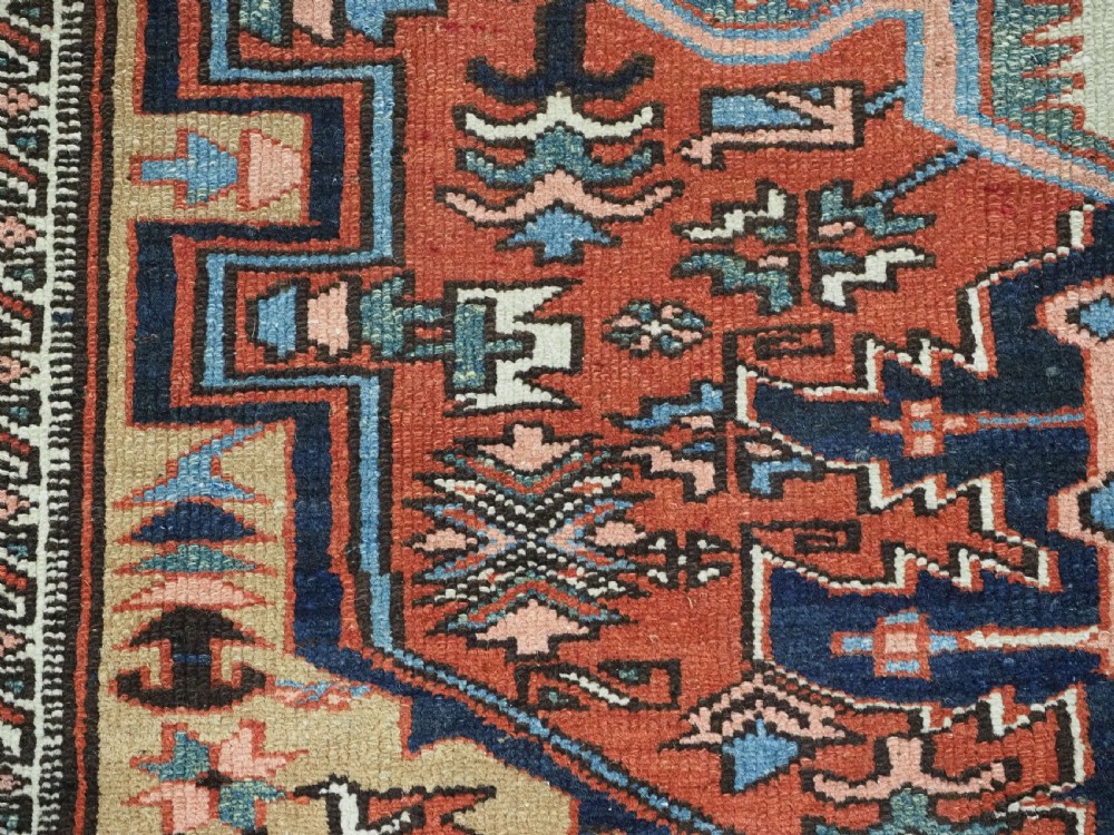 An antique hand-knotted Persian Heriz rug featuring a central starburst medallion in teal, terracotta, and cream on a patterned ground with a multi-band geometric border. View XII