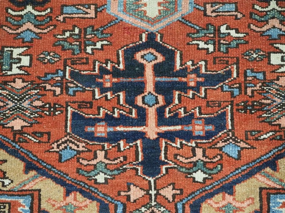 An antique hand-knotted Persian Heriz rug featuring a central starburst medallion in teal, terracotta, and cream on a patterned ground with a multi-band geometric border. View XIII