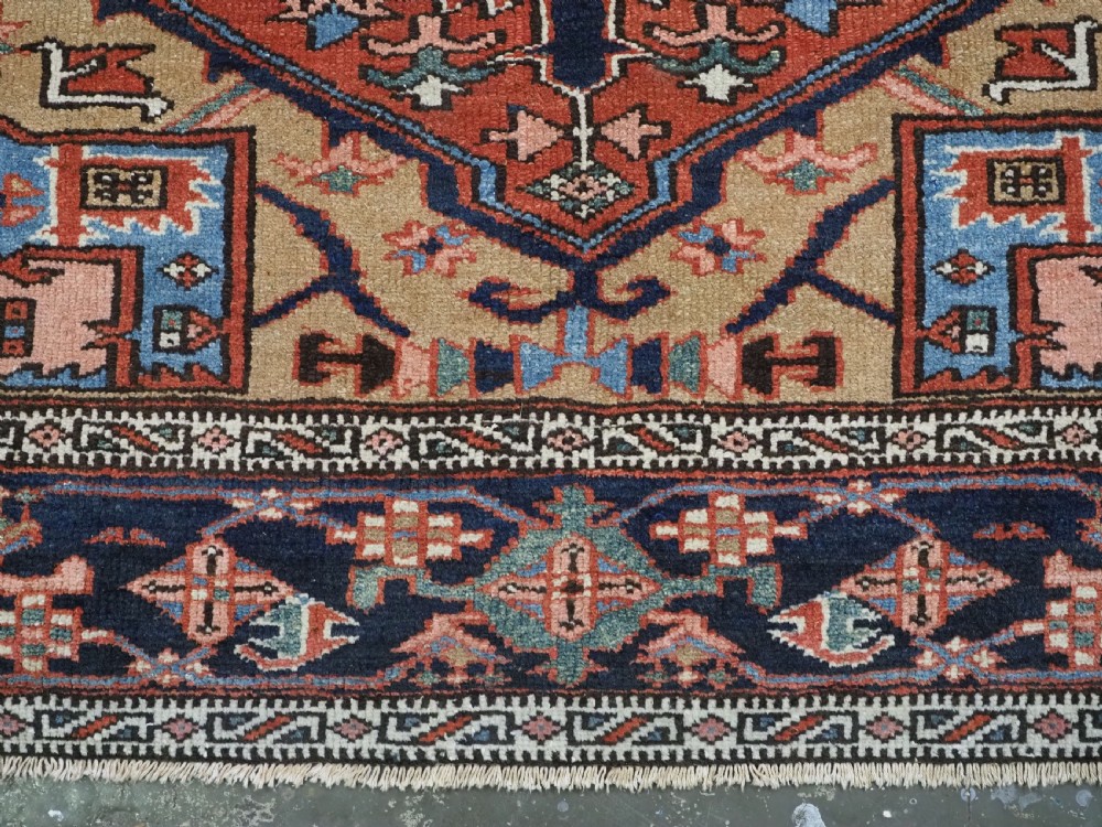 An antique hand-knotted Persian Heriz rug featuring a central starburst medallion in teal, terracotta, and cream on a patterned ground with a multi-band geometric border. View XIV
