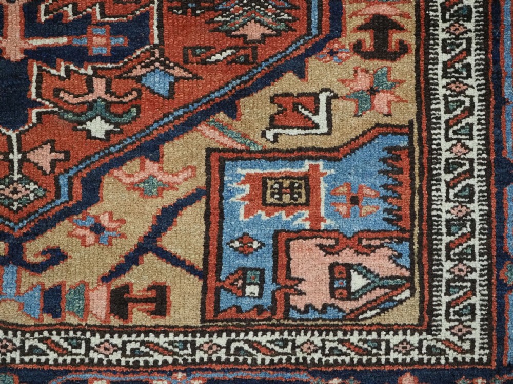 An antique hand-knotted Persian Heriz rug featuring a central starburst medallion in teal, terracotta, and cream on a patterned ground with a multi-band geometric border. View XV