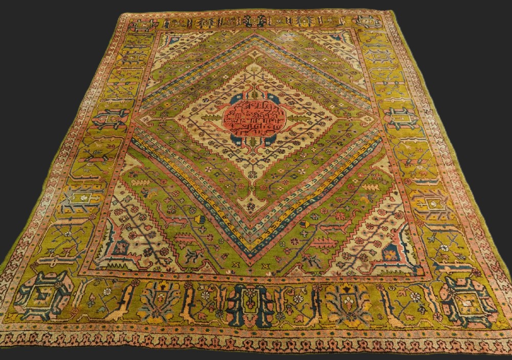 An antique Turkish Oushak wool carpet featuring an olive green field with a central cream and coral diamond medallion surrounded by detailed geometric borders. View III