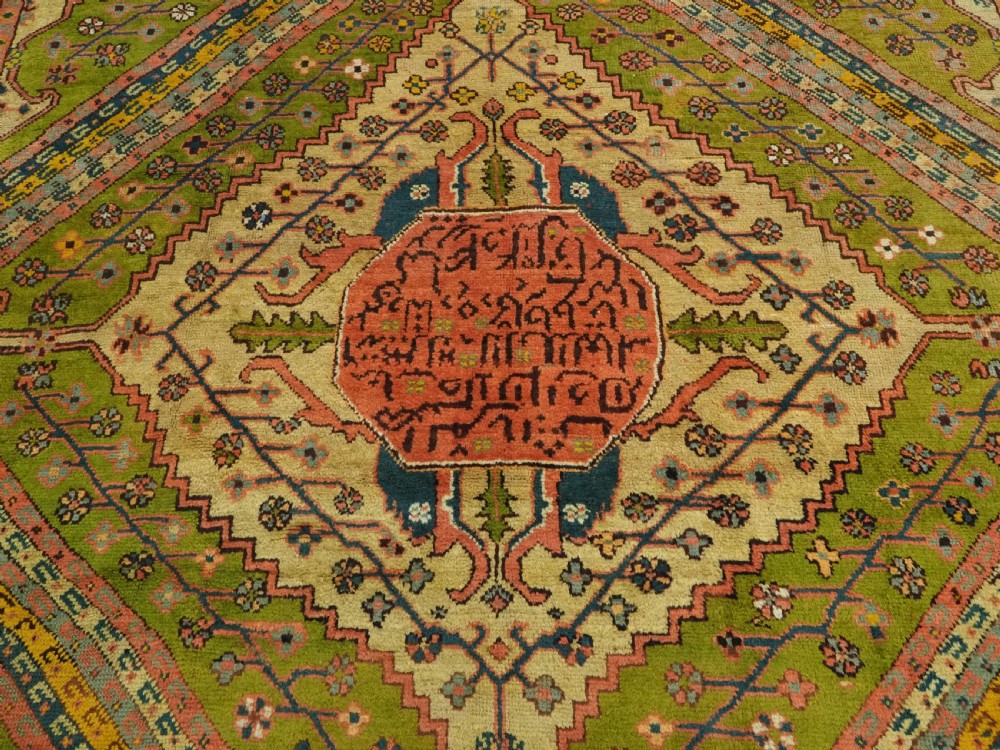 An antique Turkish Oushak wool carpet featuring an olive green field with a central cream and coral diamond medallion surrounded by detailed geometric borders. View VII