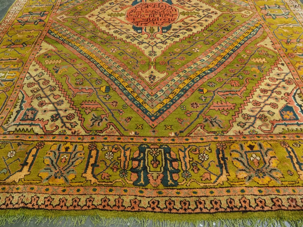 An antique Turkish Oushak wool carpet featuring an olive green field with a central cream and coral diamond medallion surrounded by detailed geometric borders. View VIII