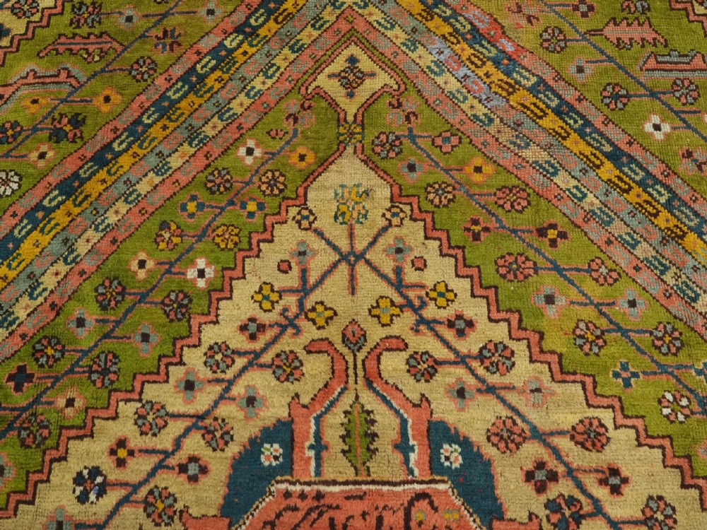 An antique Turkish Oushak wool carpet featuring an olive green field with a central cream and coral diamond medallion surrounded by detailed geometric borders. View IX