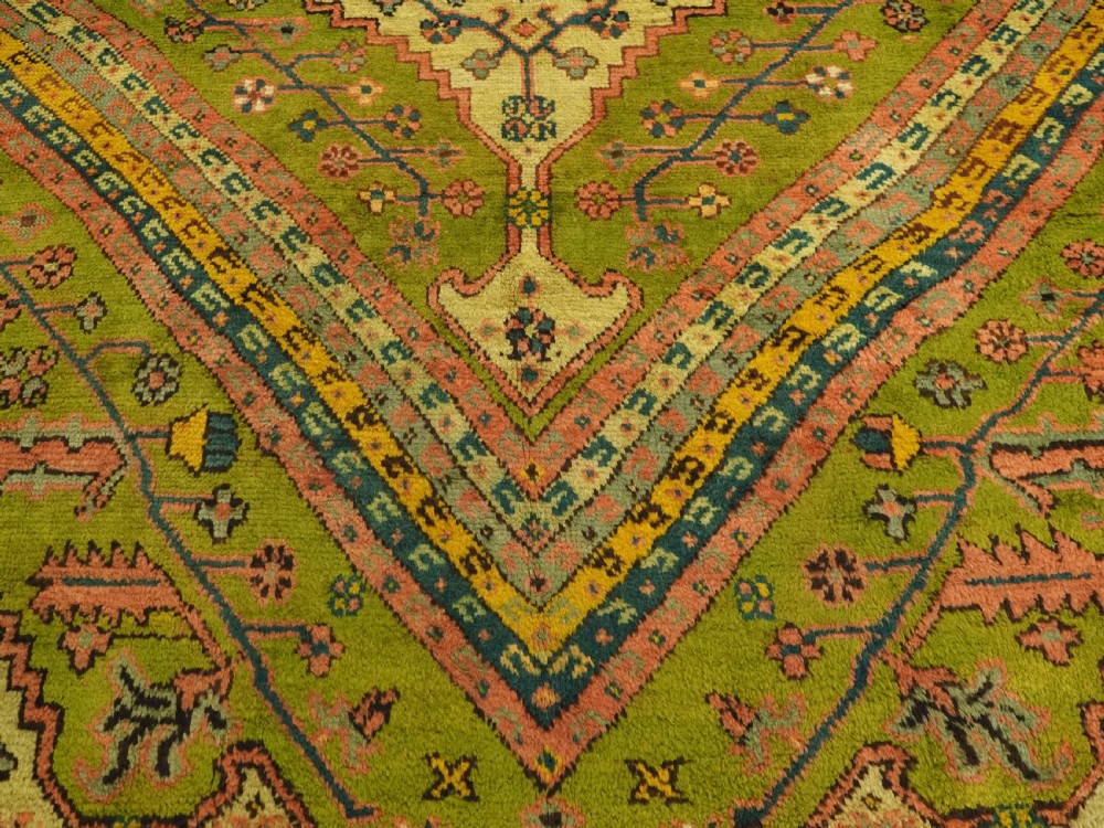 An antique Turkish Oushak wool carpet featuring an olive green field with a central cream and coral diamond medallion surrounded by detailed geometric borders. View XIII