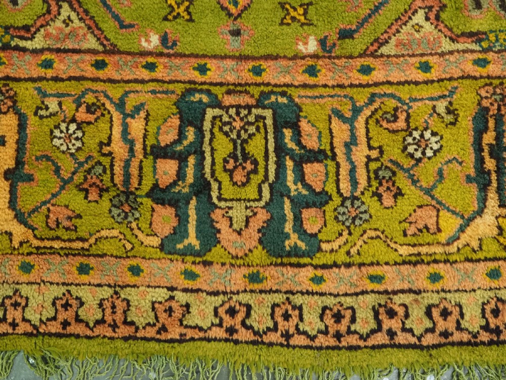 An antique Turkish Oushak wool carpet featuring an olive green field with a central cream and coral diamond medallion surrounded by detailed geometric borders. View XV