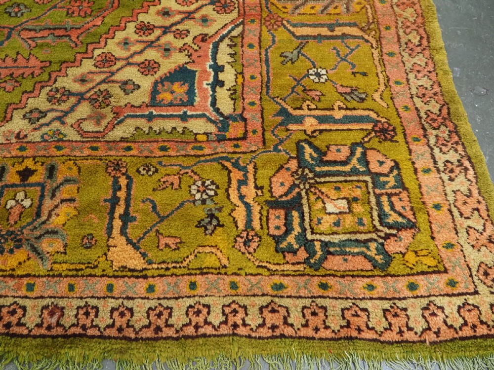 An antique Turkish Oushak wool carpet featuring an olive green field with a central cream and coral diamond medallion surrounded by detailed geometric borders. View XVI