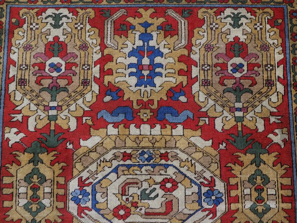 An antique hand-knotted wool rug with a central red field featuring geometric Karabagh blossom motifs and multi-tiered decorative borders. View VIII
