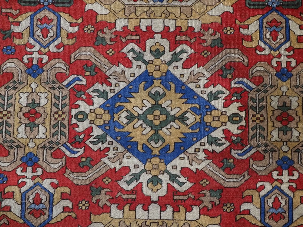 An antique hand-knotted wool rug with a central red field featuring geometric Karabagh blossom motifs and multi-tiered decorative borders. View X