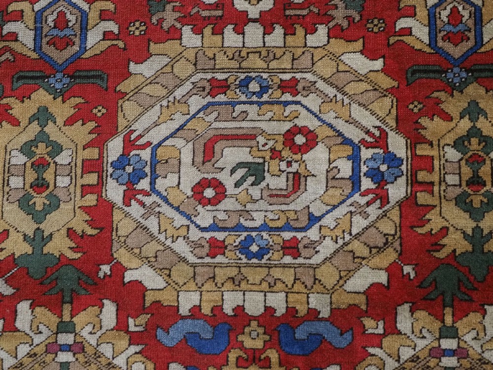 An antique hand-knotted wool rug with a central red field featuring geometric Karabagh blossom motifs and multi-tiered decorative borders. View XII