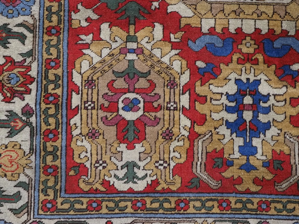 An antique hand-knotted wool rug with a central red field featuring geometric Karabagh blossom motifs and multi-tiered decorative borders. View XIII