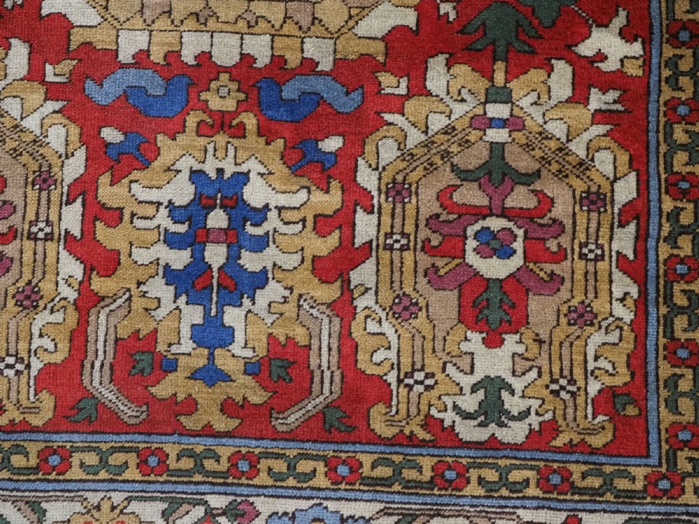 An antique hand-knotted wool rug with a central red field featuring geometric Karabagh blossom motifs and multi-tiered decorative borders. View XIV