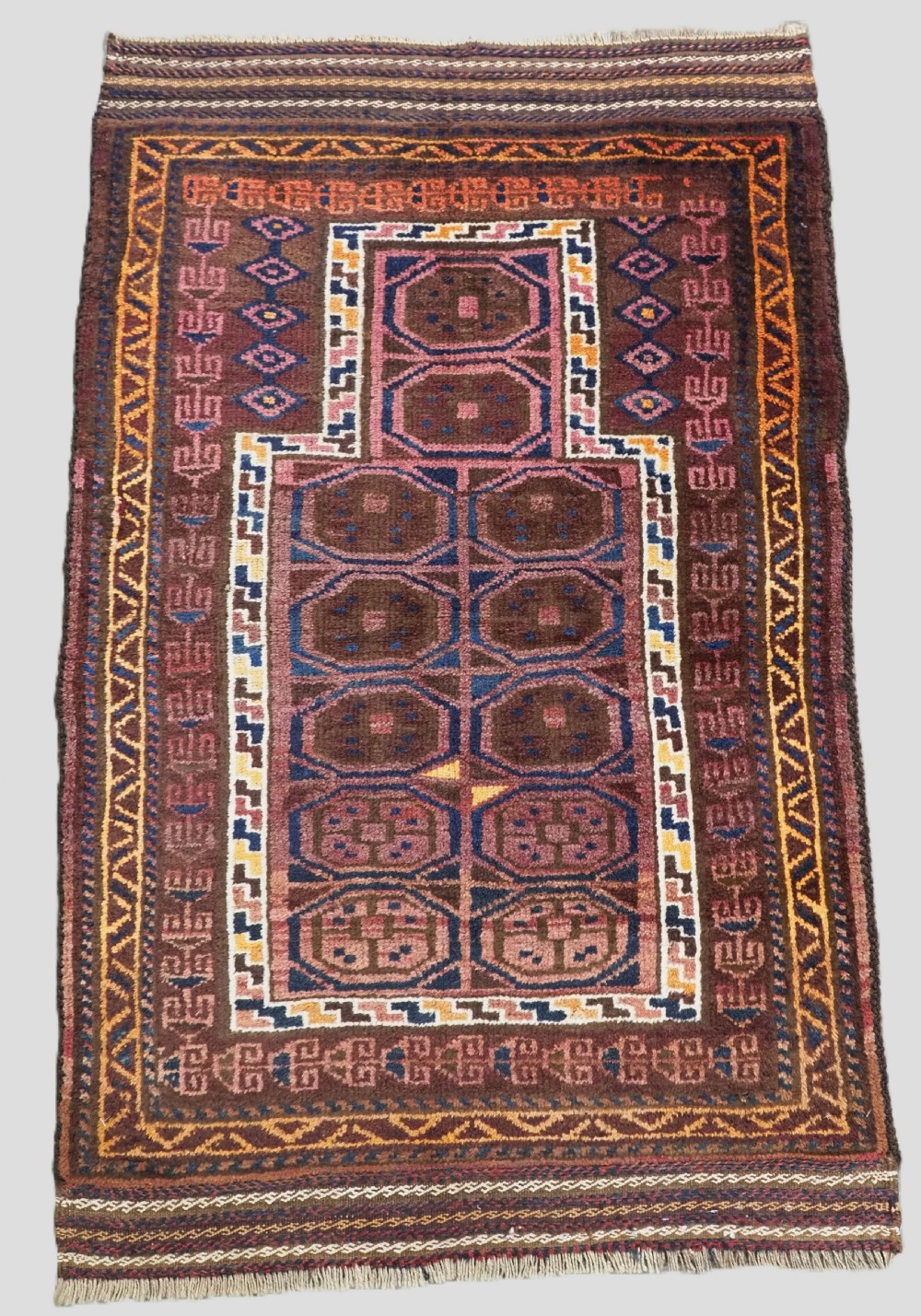 An antique hand-knotted Afghan Pashtun prayer rug featuring a dark brown background, stepped mihrab niche, geometric motifs in magenta and navy, and flat-woven kilim ends.