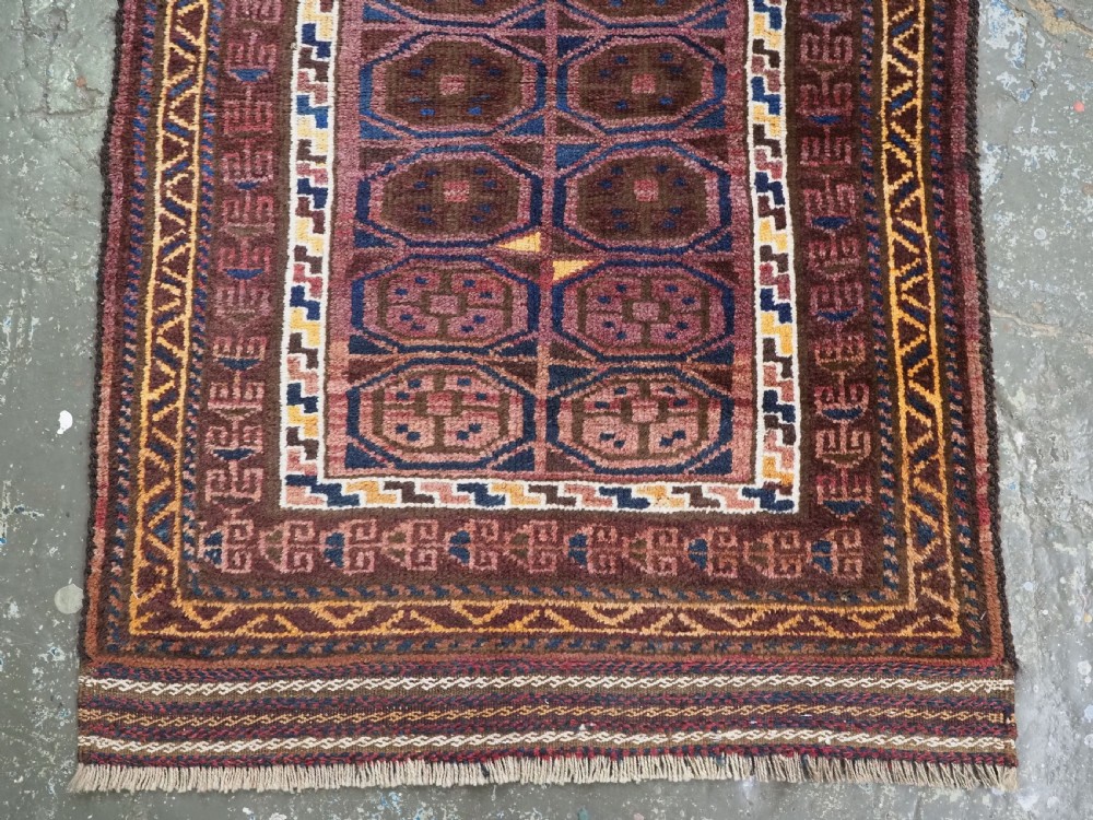 An antique hand-knotted Afghan Pashtun prayer rug featuring a dark brown background, stepped mihrab niche, geometric motifs in magenta and navy, and flat-woven kilim ends. View V