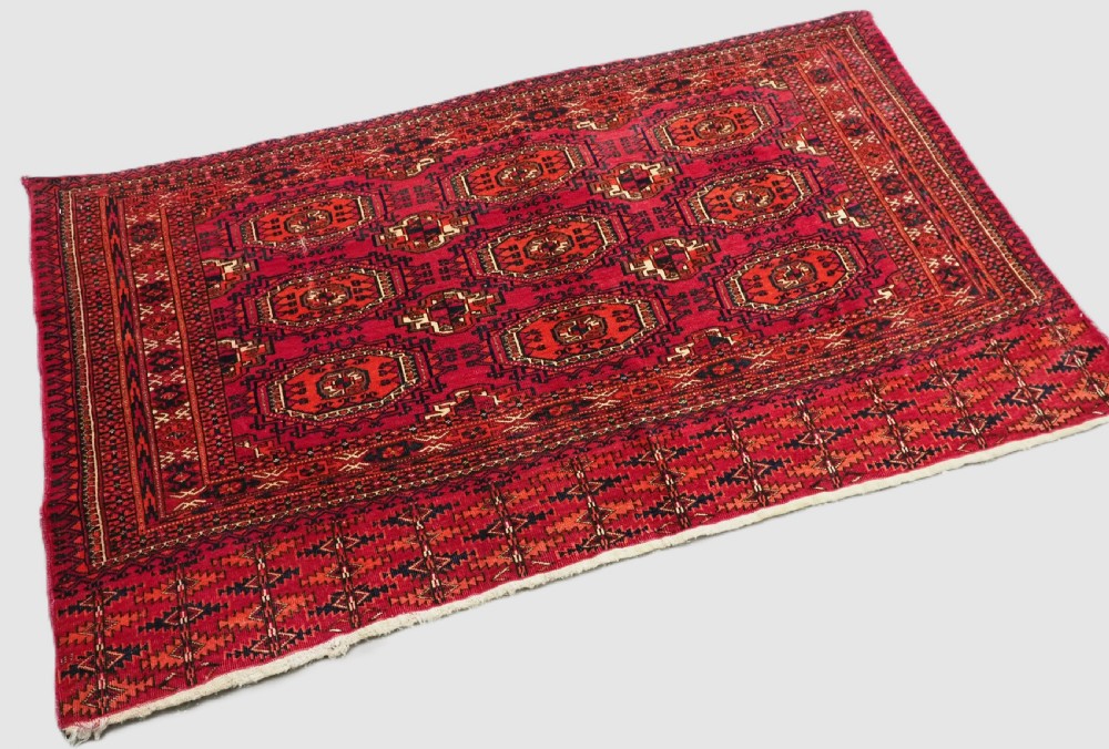 A rectangular deep red hand-knotted wool Tekke Turkmen chuval face featuring nine octagonal turreted guls surrounded by geometric borders. View II