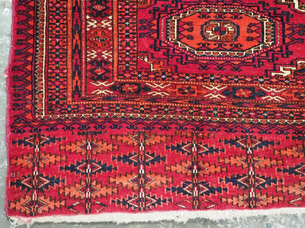 A rectangular deep red hand-knotted wool Tekke Turkmen chuval face featuring nine octagonal turreted guls surrounded by geometric borders. View IV