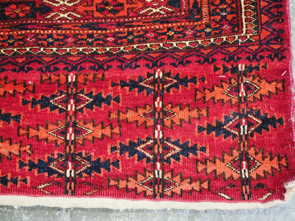 A rectangular deep red hand-knotted wool Tekke Turkmen chuval face featuring nine octagonal turreted guls surrounded by geometric borders. View VII