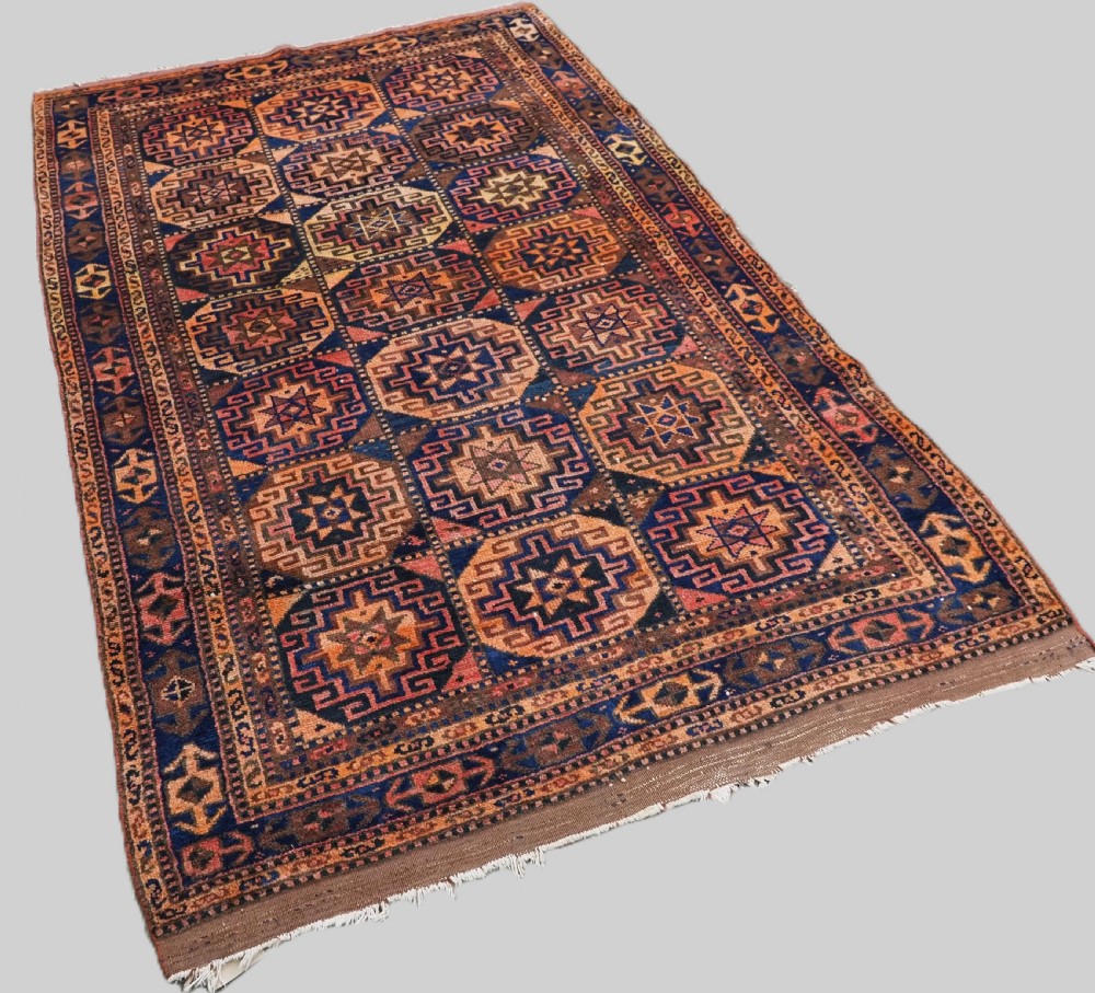 An antique Kurdish Kordi hand-knotted wool rug decorated with repeating octagonal Memlinc guls in navy blue, terracotta, and ochre. View II