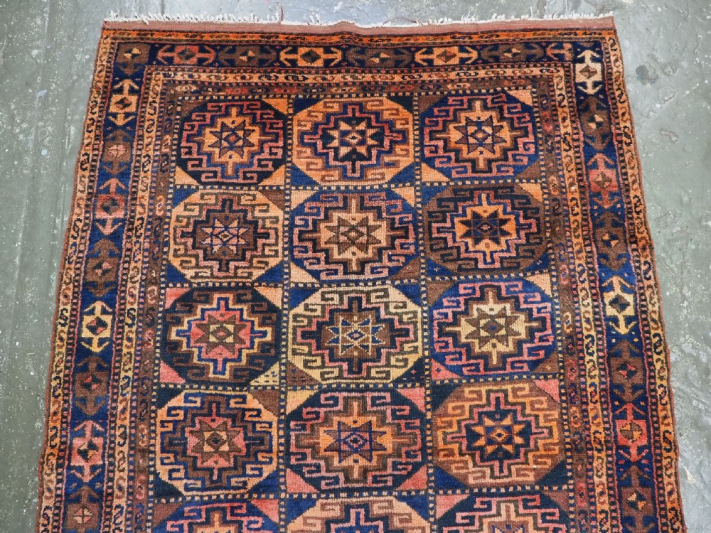 An antique Kurdish Kordi hand-knotted wool rug decorated with repeating octagonal Memlinc guls in navy blue, terracotta, and ochre. View III