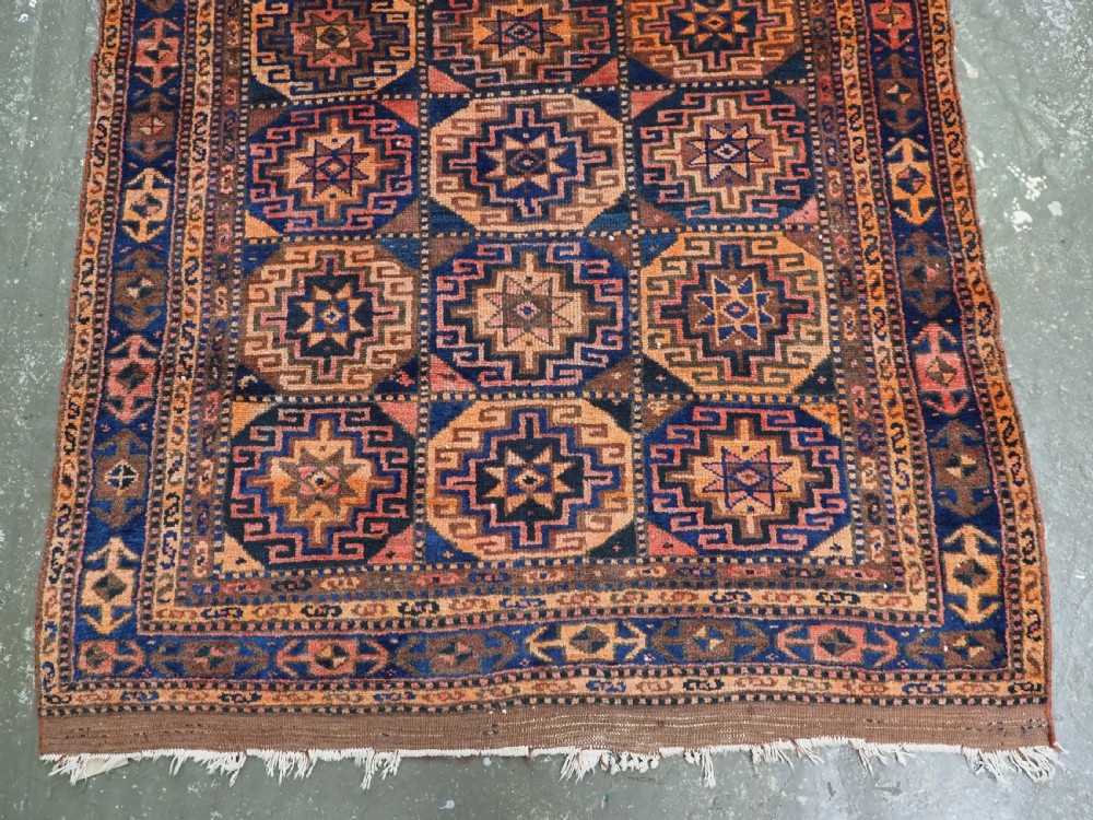 An antique Kurdish Kordi hand-knotted wool rug decorated with repeating octagonal Memlinc guls in navy blue, terracotta, and ochre. View V