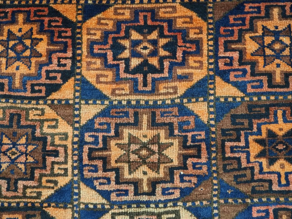 An antique Kurdish Kordi hand-knotted wool rug decorated with repeating octagonal Memlinc guls in navy blue, terracotta, and ochre. View VIII