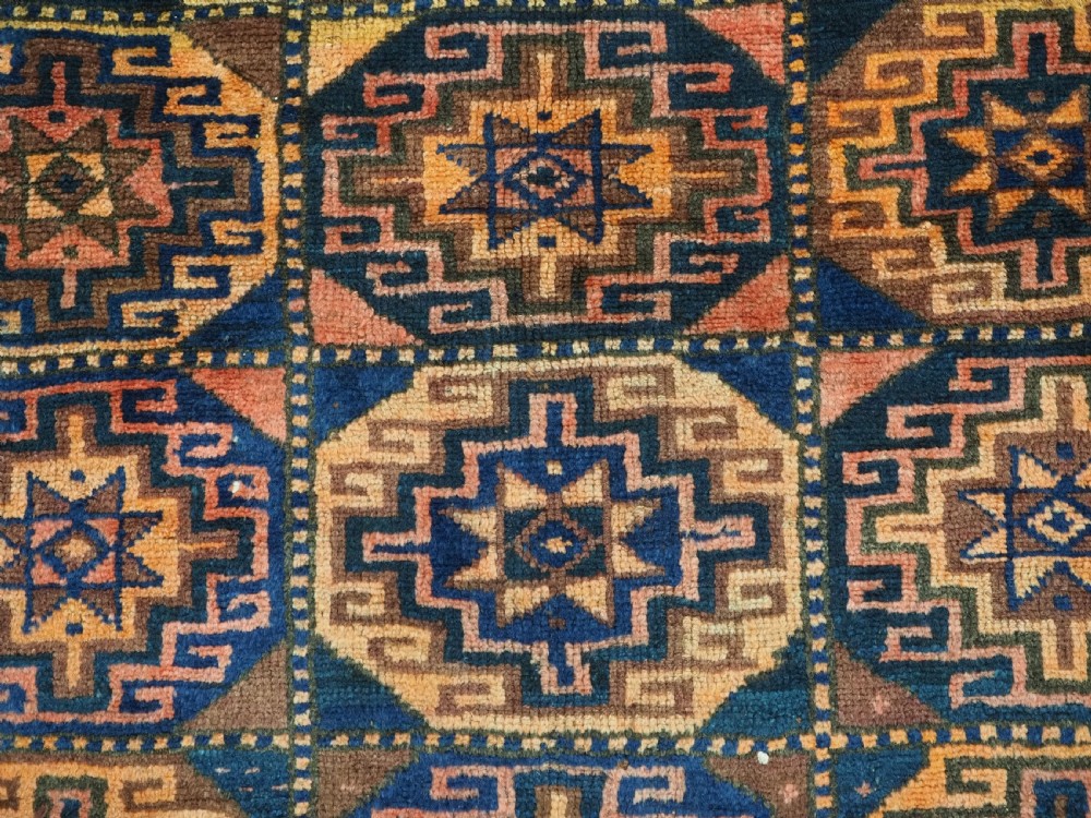 An antique Kurdish Kordi hand-knotted wool rug decorated with repeating octagonal Memlinc guls in navy blue, terracotta, and ochre. View IX
