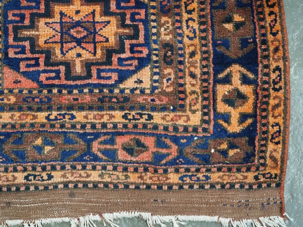 An antique Kurdish Kordi hand-knotted wool rug decorated with repeating octagonal Memlinc guls in navy blue, terracotta, and ochre. View XI