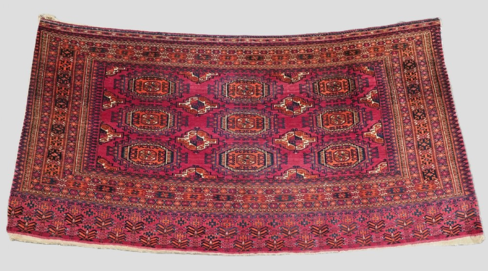 An antique crimson red wool Tekke Turkmen chuval featuring nine central octagonal gul motifs and a plain weave back.