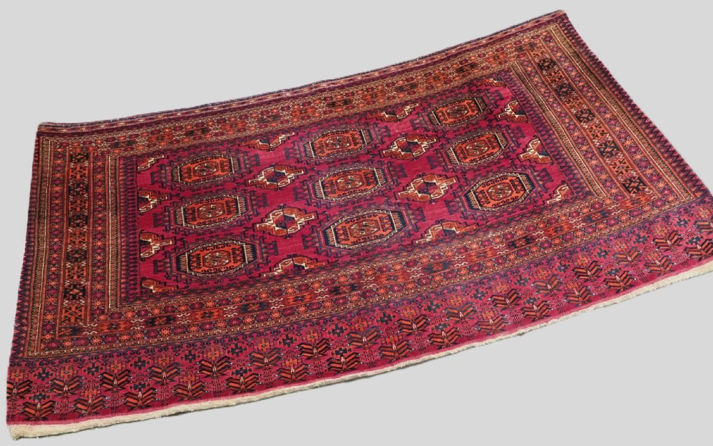 An antique crimson red wool Tekke Turkmen chuval featuring nine central octagonal gul motifs and a plain weave back. View II