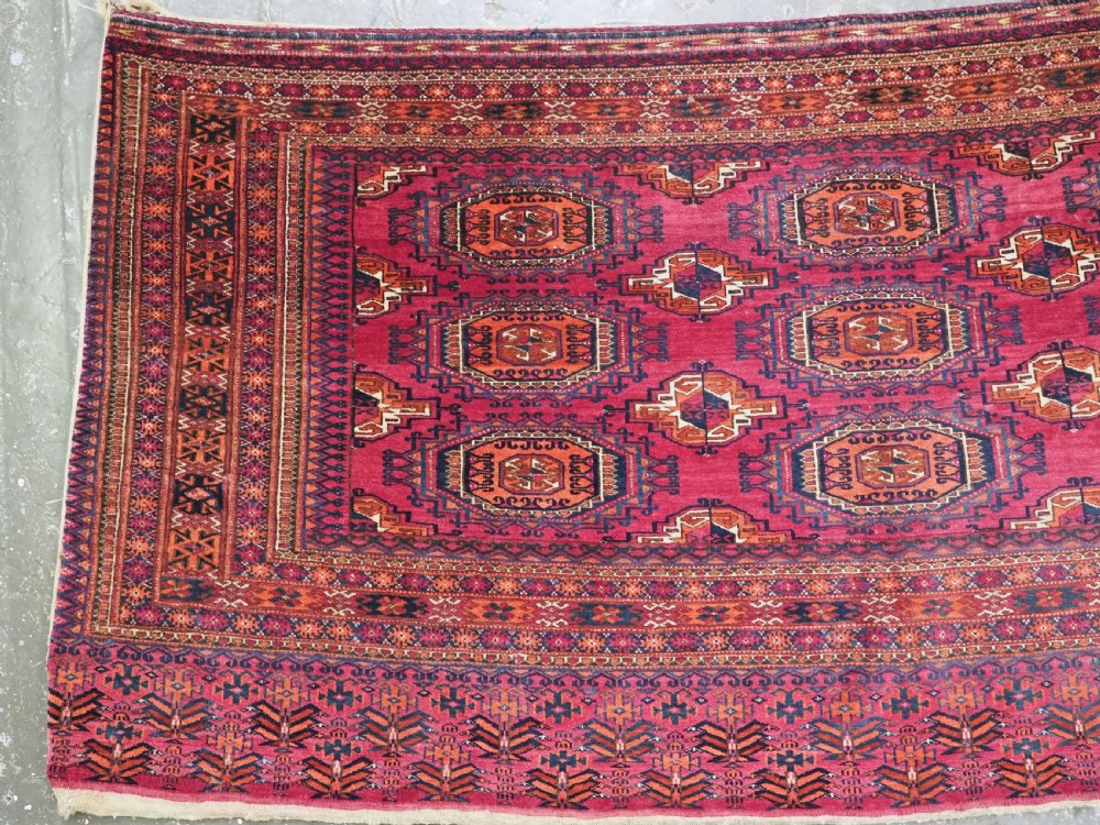 An antique crimson red wool Tekke Turkmen chuval featuring nine central octagonal gul motifs and a plain weave back. View III