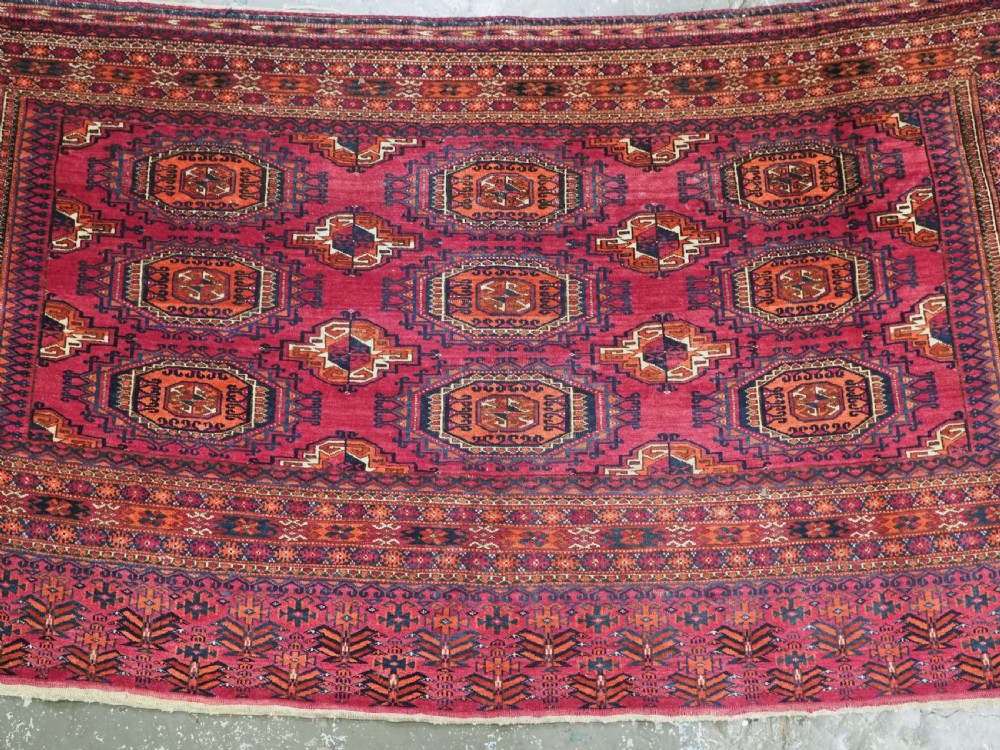 An antique crimson red wool Tekke Turkmen chuval featuring nine central octagonal gul motifs and a plain weave back. View IV