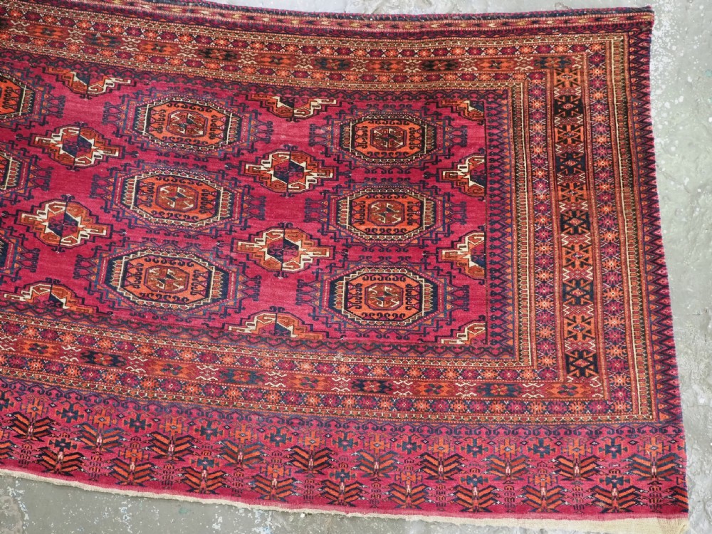 An antique crimson red wool Tekke Turkmen chuval featuring nine central octagonal gul motifs and a plain weave back. View V