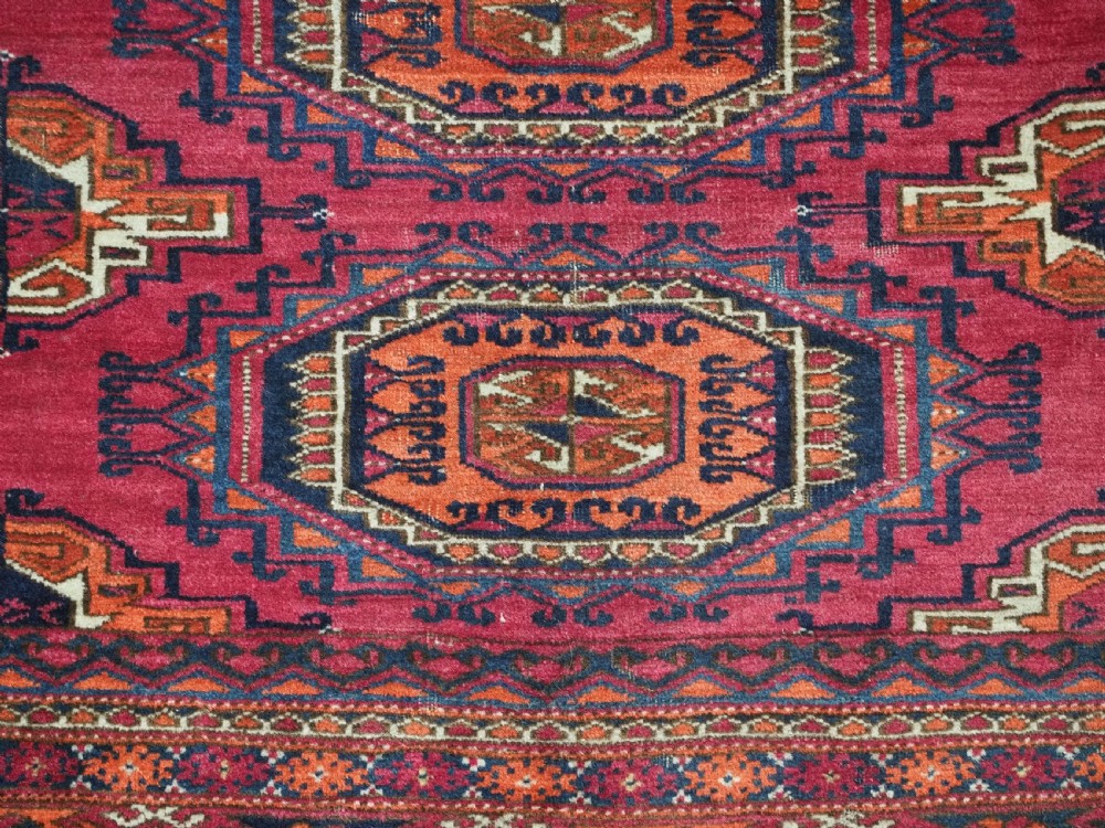 An antique crimson red wool Tekke Turkmen chuval featuring nine central octagonal gul motifs and a plain weave back. View IX