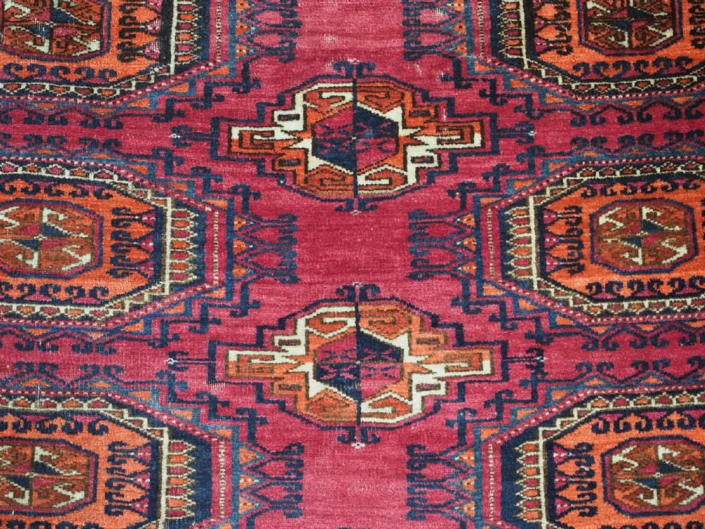 An antique crimson red wool Tekke Turkmen chuval featuring nine central octagonal gul motifs and a plain weave back. View X
