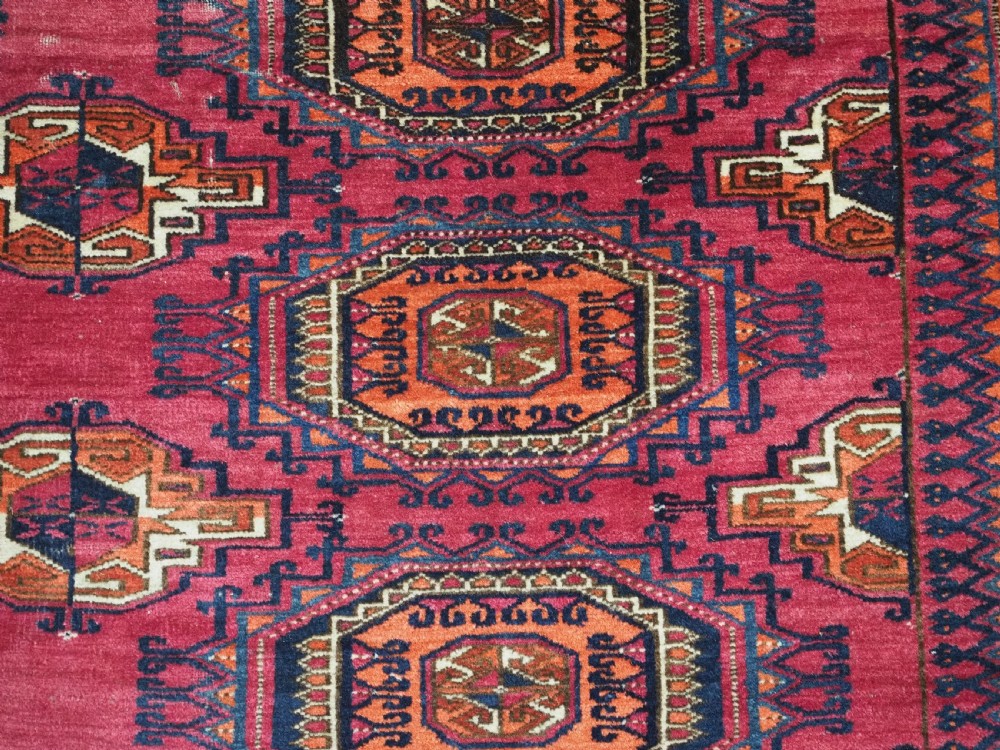 An antique crimson red wool Tekke Turkmen chuval featuring nine central octagonal gul motifs and a plain weave back. View XI