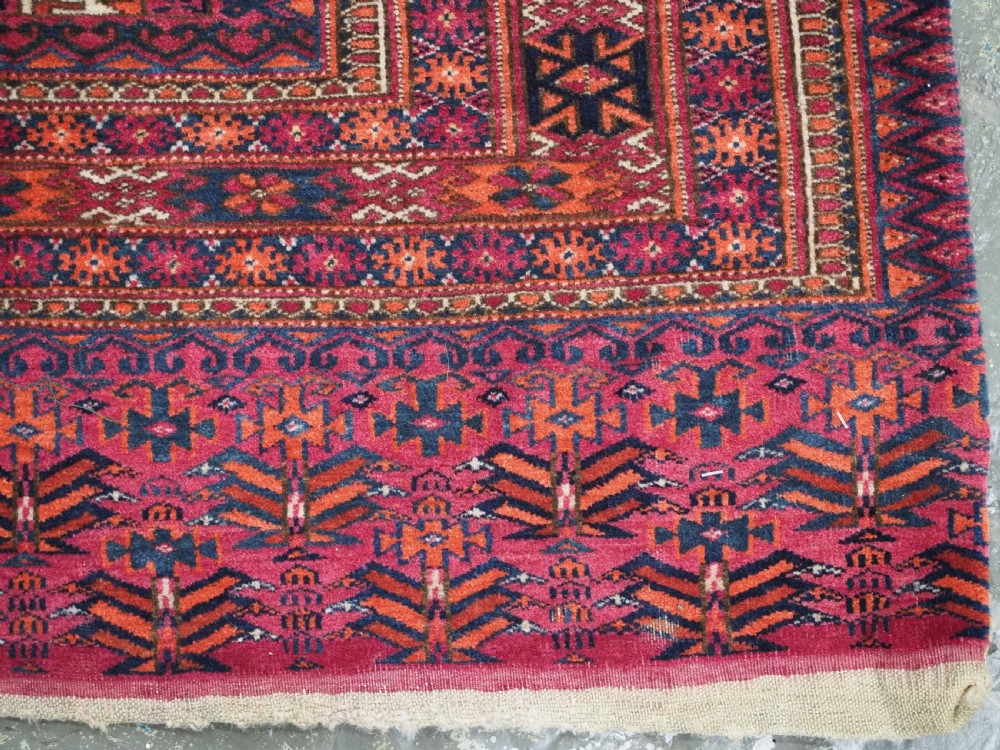 An antique crimson red wool Tekke Turkmen chuval featuring nine central octagonal gul motifs and a plain weave back. View XII