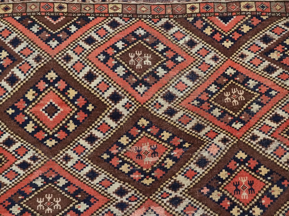 An antique Central Asian hand-woven wool rug featuring a repeating diamond lattice pattern in terracotta, dark brown, cream, and deep blue. View VIII