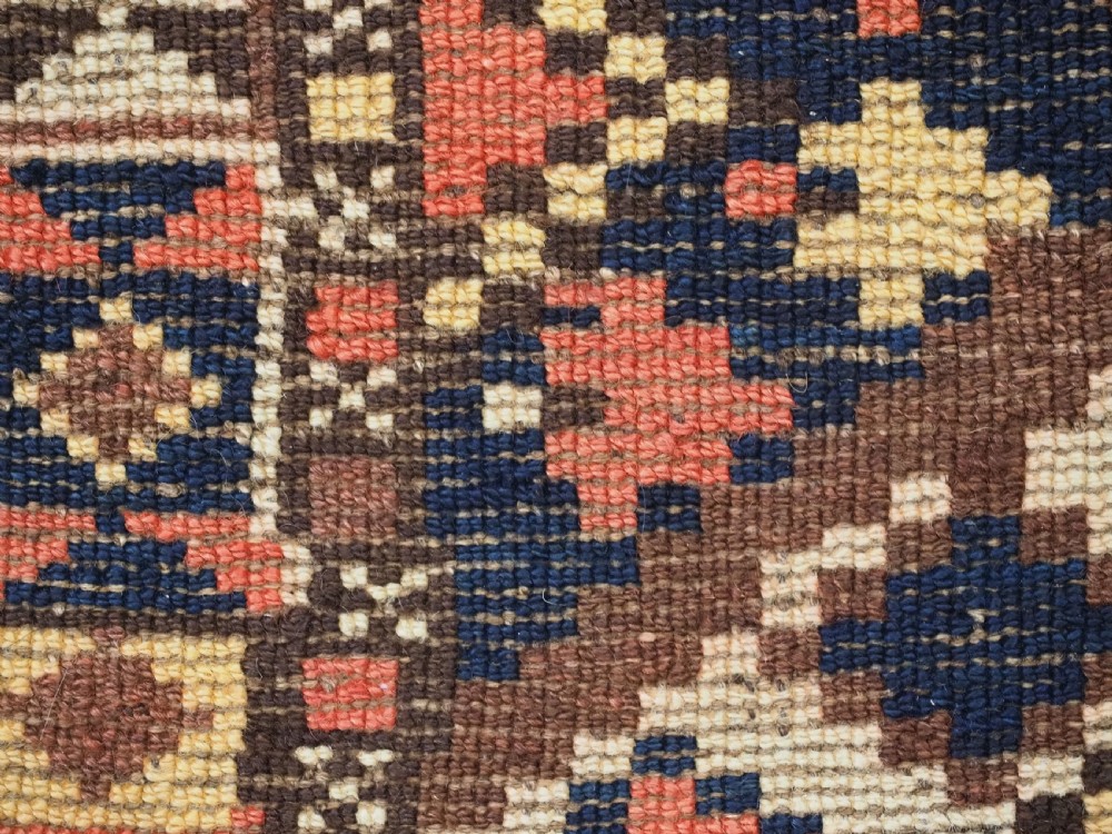 An antique Central Asian hand-woven wool rug featuring a repeating diamond lattice pattern in terracotta, dark brown, cream, and deep blue. View XIII