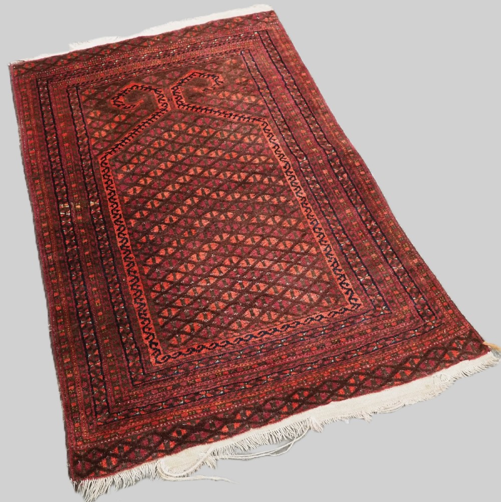 An antique red wool Turkmen prayer rug featuring a geometric diamond lattice pattern and a distinctive rams horn arch at the top. View II