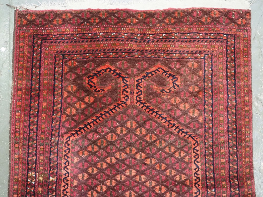An antique red wool Turkmen prayer rug featuring a geometric diamond lattice pattern and a distinctive rams horn arch at the top. View III