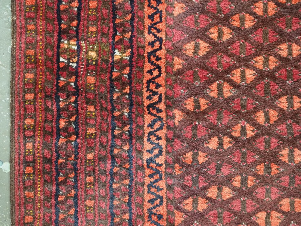 An antique red wool Turkmen prayer rug featuring a geometric diamond lattice pattern and a distinctive rams horn arch at the top. View VII