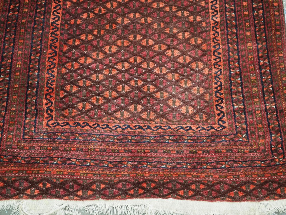 An antique red wool Turkmen prayer rug featuring a geometric diamond lattice pattern and a distinctive rams horn arch at the top. View VIII