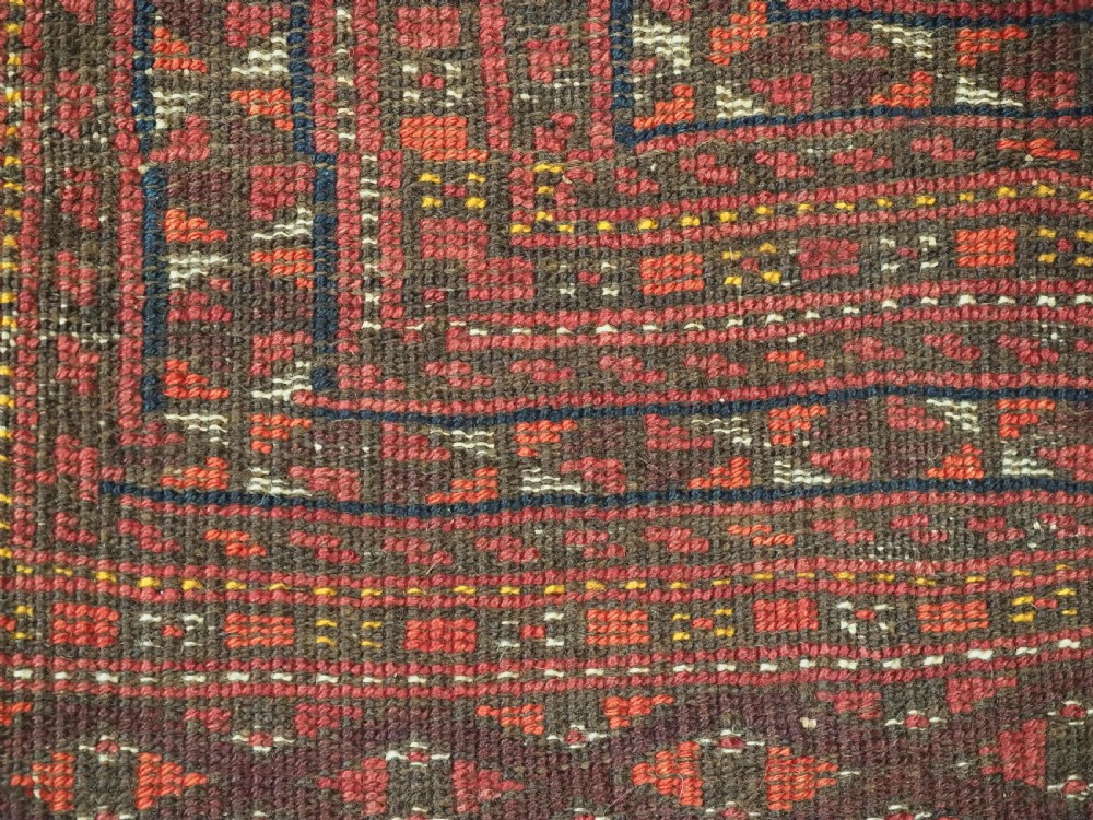 An antique red wool Turkmen prayer rug featuring a geometric diamond lattice pattern and a distinctive rams horn arch at the top. View X