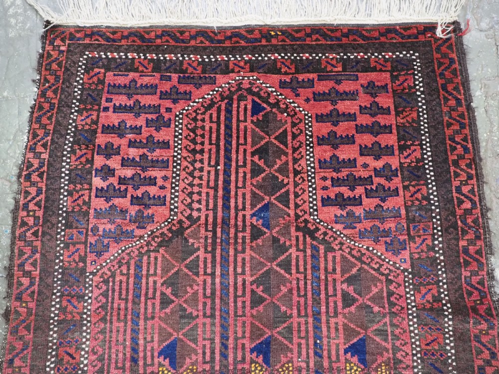 An antique Afghan wool prayer rug displaying a dark brown field with geometric lattice patterns framed by a terracotta arch motif. View III