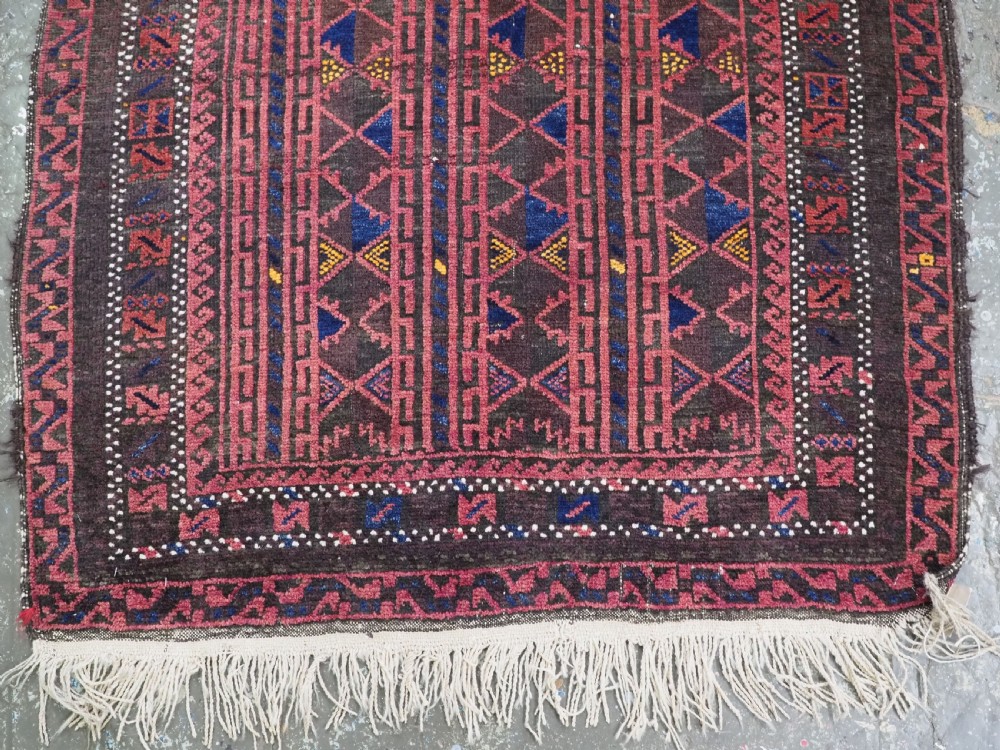An antique Afghan wool prayer rug displaying a dark brown field with geometric lattice patterns framed by a terracotta arch motif. View V
