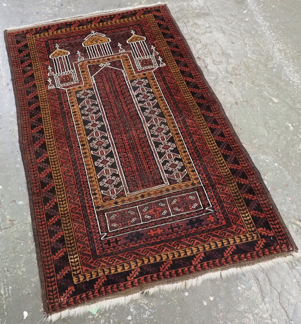 An antique hand-knotted Afghan Baluch wool prayer rug featuring a triple mihrab architectural design in burgundy, brown, ochre, and white tones. View II