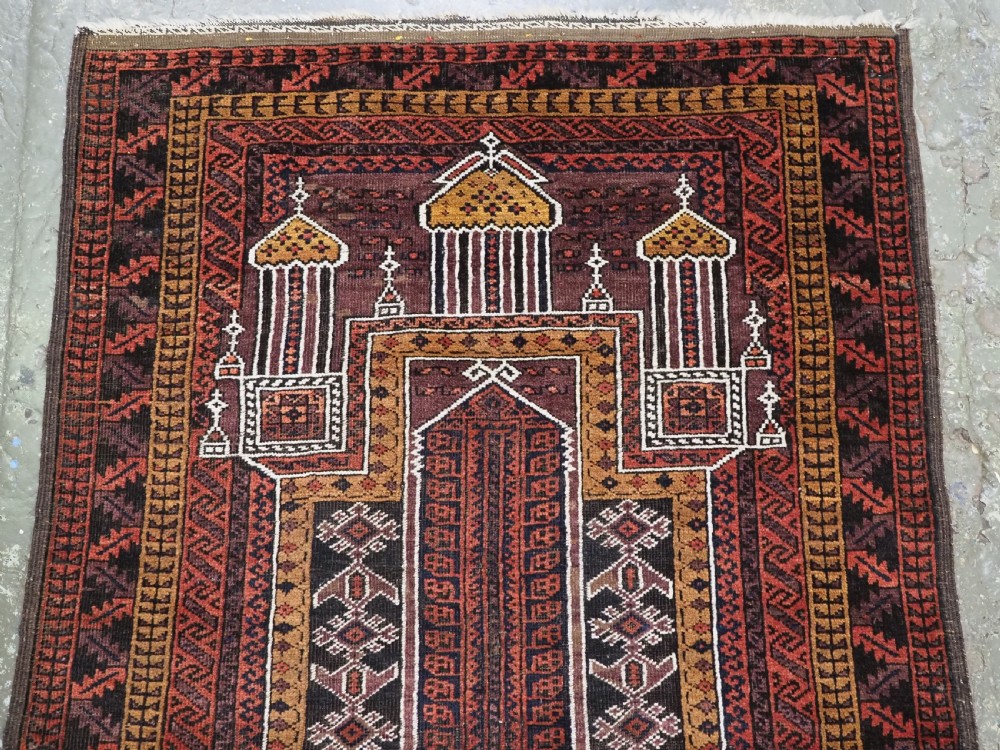 An antique hand-knotted Afghan Baluch wool prayer rug featuring a triple mihrab architectural design in burgundy, brown, ochre, and white tones. View III